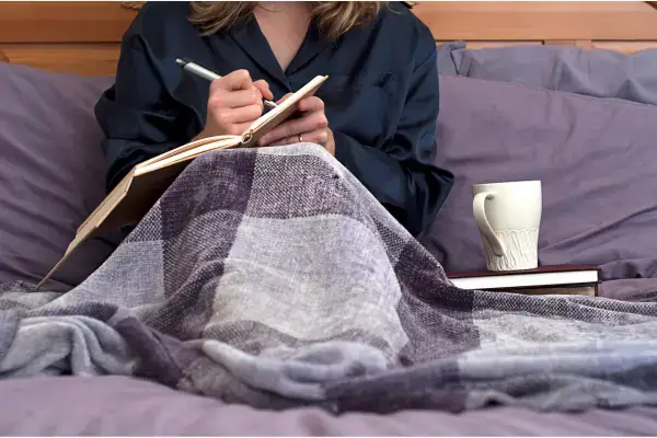 A woman writing a dream journal in bed